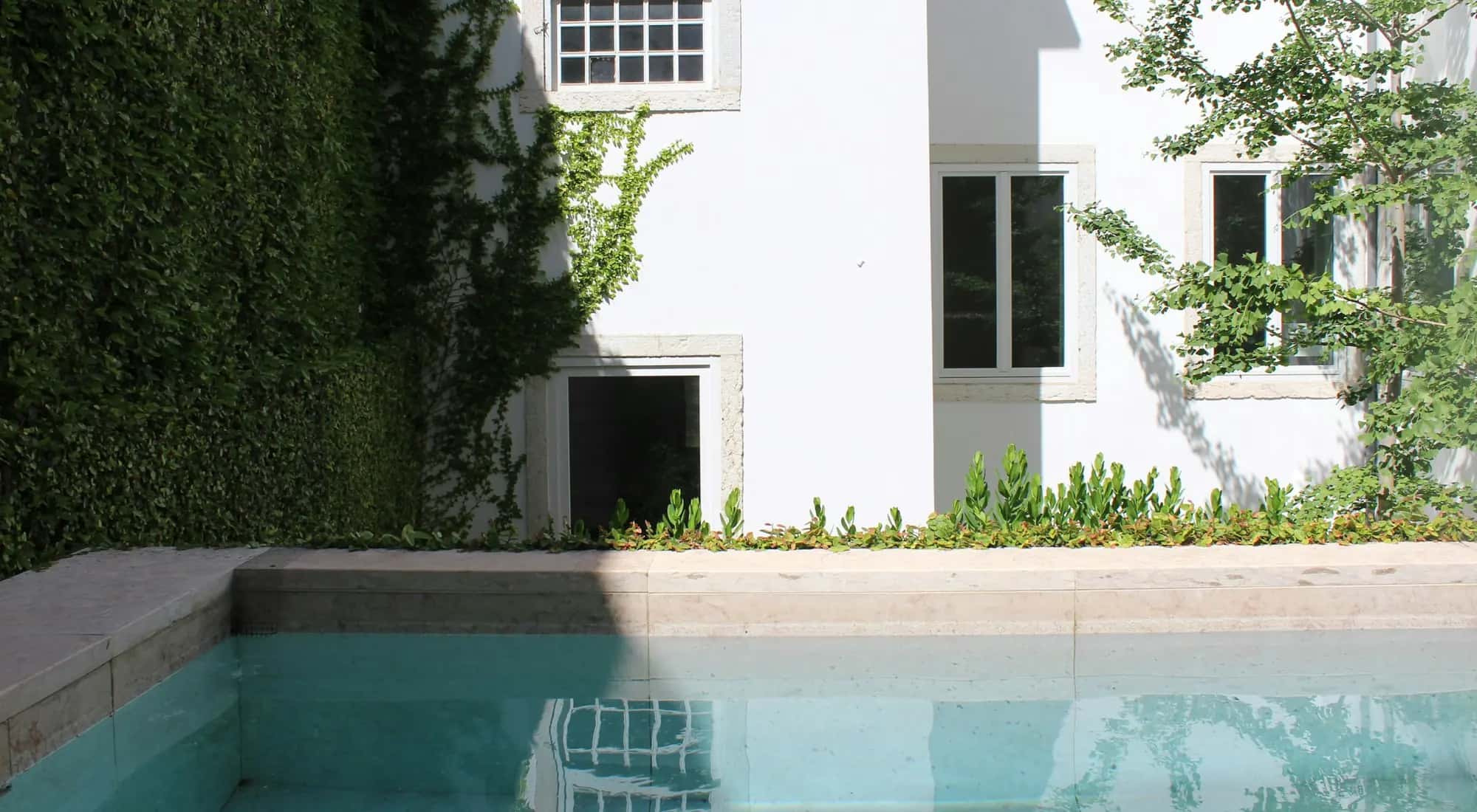Piscina junto a una casa blanca